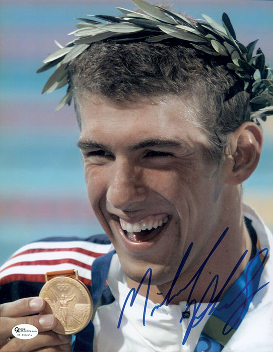 Farbfoto mit Originalsignatur von Michael Phelps (USA). Sportsuperstar. Er gilt als der vielseitigste Schwimmer der Gegenwart und ist mit 28 olympischen Medaillen, davon 23-mal Gold, der mit weitem Abstand erfolgreichste Olympionike der Geschichte. Gibt kaum Autogramme! 15,5x10,5 cm.