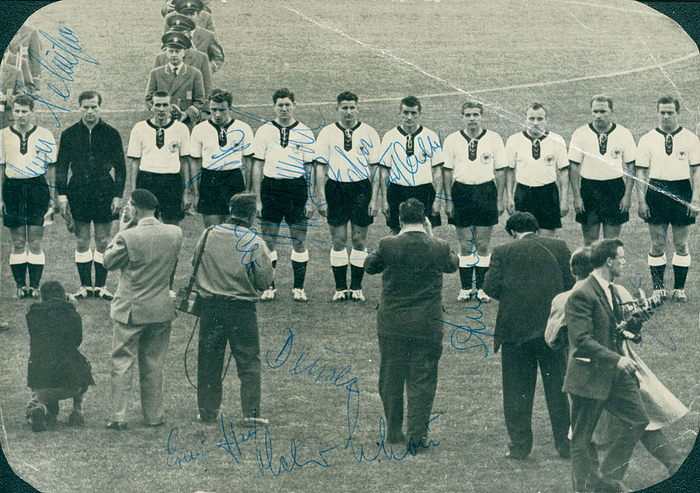 S/W-Großpostkarte "Deutsche Nationalmannschaft in Schweden" (Rückseitiger Aufdruck) bei der Fußball-Weltmeisterschaft 1958. 21x15 cm. Mit 8 original Signaturen der Spieler (Hans Schäfer, Alfred "Aki" Schmidt , Syzmaniak, Helmut Rahn, Fritz Walter, Stollenwerk, Juskowiak) und drei Signaturen der Betreuer: Helmut Schön, Deuser und ein weiterer.