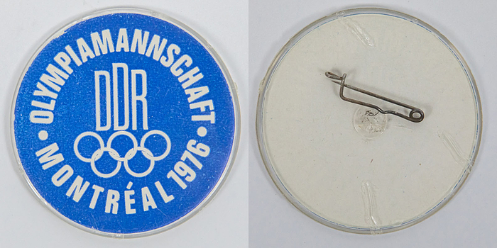 „Olympiamannschaft DDR Montreal 1976". Offizielles Abzeichen der Olympiamannshaft der DDR für die Olympischen Sommerspiele 1976. Kunststoff mit Metallnadel, 5,5 cm.