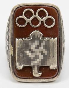 Massiver Silberring. Mit aufgesetzten silbernen Olympischen Ringen und einem Reichsadler mit Hakenkreuz montiert auf einem Bernsteinplättchen. Ring an den seutlichen Ringschienen mit Eichenblättern verziert. Silber (gepunzt 835er, Gewicht 20 Gramm). 3x2x2,5 cm. - Bild 2