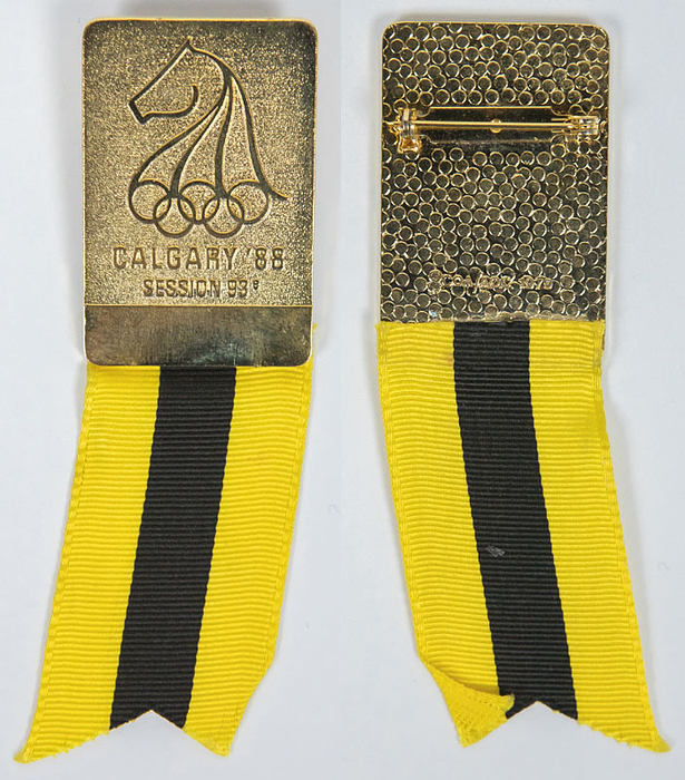 Teilnehmer-Abzeichen der 93e Session I.O.C. Calgary 1988. Bronze vergoldet, mit gelb-schwarzen Seidenband, 9x3 cm.