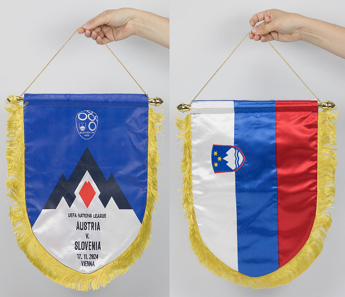 Original Spielwimpel der Natinalmannschaft von Slowenien mit aufgestickten match Details "UEFA Nations League Austria v Slovenia 17.11.2024 Vienna" (Österreich v Slowenien in Wien). Bedruckter Seidenwimpel mit Seidenfransen. Rückseite in den Landesfarben und einem besticktem aufgesetztem Landeswappen. Vergoldete Kunststoffstange, 45x35 cm.