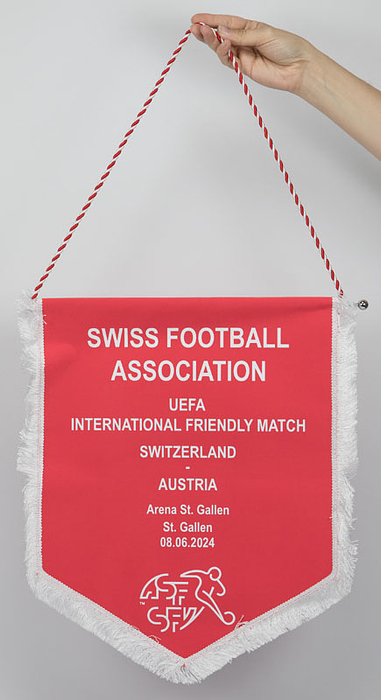Original Spielwimpel der schweizer Nationalmannschaft vom Fußballspiel Schweiz v Österreich am 08.06.2024 in St-Gallen. Bedruckte Kunstseide. Seidenfransen und rot-weißes Schlaufenband. Verchomte Metalstange mit Kugeln. 43x38 cm.