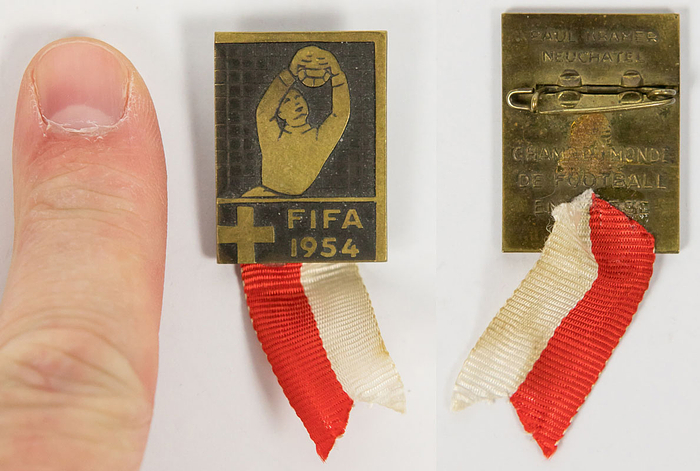 Großes, offizielles Besucherabzeichen Fußball WM 1954. „FIFA 1954“ Bronze mit Rot-weißen Seidenband. Dieses Abzeichen wurde nur an Ehrengäste der FIFA vergeben!!!! Hersteller: Paul Kramer Zürich und Aufschrift „Champ. du Monde de Football“. 2,9x2,1 cm.