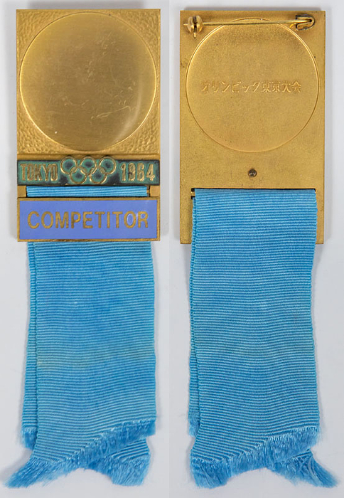 Offizielles Teilnehmerabzeichen Tokyo 1964 „Competitor“ (Athlet) für Schwimmen. Bronze, vergoldet. Schriftleiste hellblau emailliert. Seidenband hellblau. 12x3,8cm.