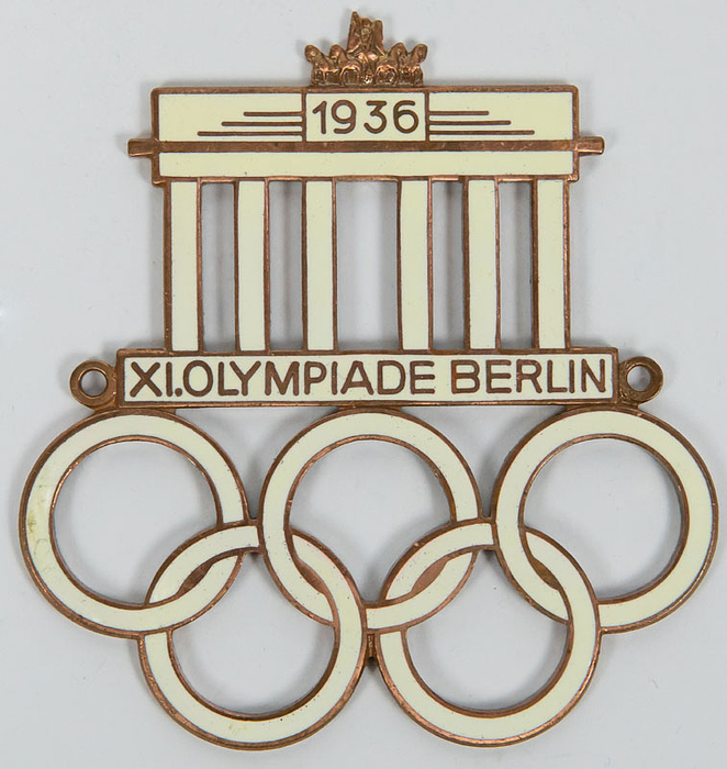 Autoplakette mit Brandenburger Tor und den Olympischen Ringen, "XI.Olympiade Berlin 1936". Mit Herstellerpunze! Bronze, vergoldet, weiß emailliert. 7,5x7,2 cm.
