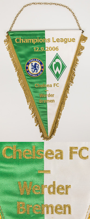 Original Spielwimpel mit golden gestickter Schrift „Champions League 12.9.2006. Chelsea FC - Werder Bremen“ mit aufgestickten Vereinsemblemen beider Teams. Seidenwimpel mit goldenen Seidenfransen, Metallkette und Metallstange. 41x28cm.