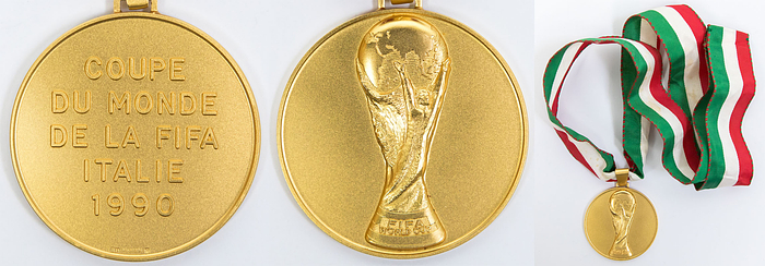 Offizielle Siegermedaille der deutschen Fußball-Nationalmannschaft für den Sieg bei der Fußball-Weltmeisterschaft 1990 in Italien. Coupe du monde de la FIFA Italie 1990“ Gold (gepunzt, 585er, Gewicht: 78 Gramm) mit original, dreifarbigem Seidenband. Hersteller: Hugenin. 5 cm. Persönliches Exemplar des Fußball Weltmeisters Thomas Häßler. Häßler bestätigt mit einem Echtheitszertifikat (COA), dass dieses Stück aus seiner Sammlung gekommen ist.