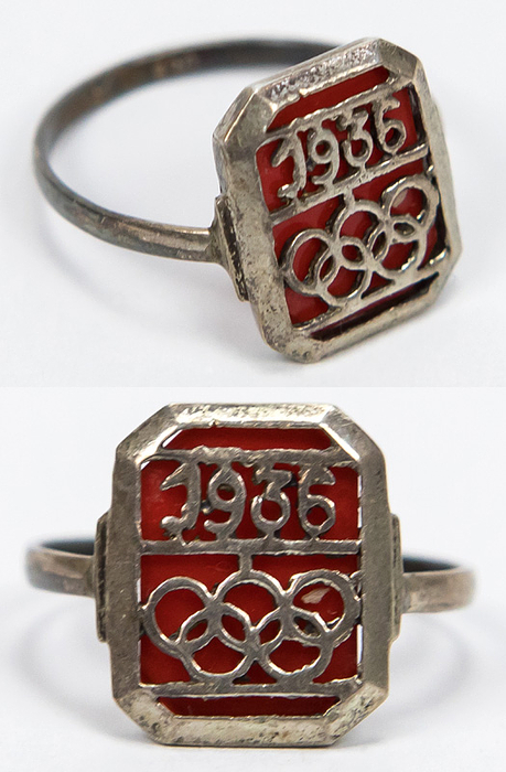 Ring OSS1936  | Ring anlässlich der Olympischen Spielen Berlin 1936 Olympischen Ringen und der Inschrift "1936". versilbert, Ringdurchmesser 20mm. Versilbert mit Bernsteinimitat. Bildseite: 1,5x1,1 cm.
