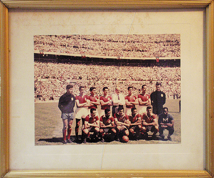  - Benfica Lissabon 1962. Original Coloured photo (23x17.5) of the team. It once hung, framed (33x27.5 cm),in Bela Guttman's living room in Vienna. Gift from Benifca to Bela Guttmann and the players. Guttmann estate 2001 No. 272 -- The frame shows signs of useage, the photo is slightly faded and the glass now has a small crack. Condition: A-C