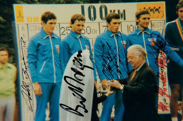 DDR OSS1980 Radsport  | Silbermedaille für die DDR im Radsport bei den Olympischen Spielen 1980 im Mannschaftszeitfahren. Farbreprofoto mit den original Signaturen von Falk Boden (3facher Weltmeister), Bernd Drogan (3facher Weltmeister), Olaf Ludwig (Gold 1988; Grünes Trikot Tour de France 1990), Hans-Joachim Hartnick (Sieger Friedensfahrt 1976 + Weltmeister 1979). KOMPLETTES TEAM. 18x12,5 cm