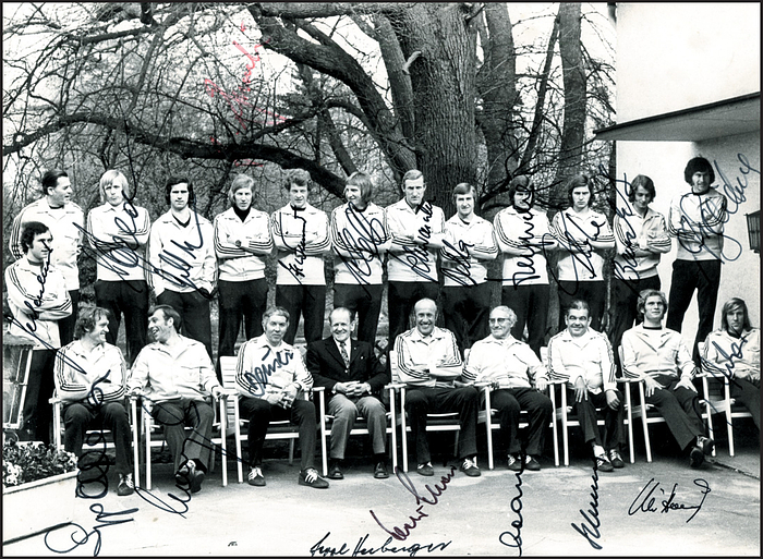 Nationalmannschaft 1974  | s/w-Pressefoto (Horst Müller) mit der deutschen Nationalmannschaft bei einem Vorbreitungslehrgang zur Fußball - Weltmeisterschaft 1974 mit 16 Originalsignaturen der deutschen DFB-Elf der Fußball-Weltmeisterschaft 1974 und 5 Signaturen von Betreueren (dabei: Helmut Schön und Sepp Herberger). Unterschrift von Gerd Müller fehlt. 24x18 cm.