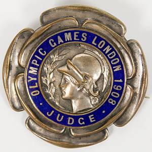 Teilnehmerabzeichen 1908  | Offizielles Teilnehmerabzeichen für die Olympischen Spiele 1908 in London mit der Aufschrift "Olympic Games London 1908 Judge" (Jury).  Bronze, versilbert, blau emailliert, Hersteller: "Vaughton,Birmingham", 5,7 cm. - Bild 2
