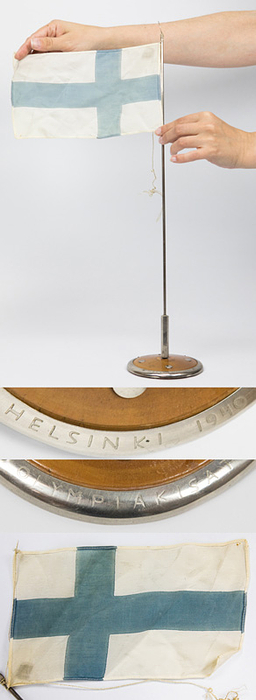 Olympic Games Heslinki 1940 Commemorativ flagpole - Miniature flagpole on a base with a Finnish flag made of linen (22 x 13 cm). The pole base has a silver-plated border engraved with "Helsinki 1940" and "Olympiakisat." The flagpole's base is chrome-plated. Height: 50 cm. --Very rare and decorative souvenir of the cancelled 1940 Olympic Games in Helsinki. Condition: B