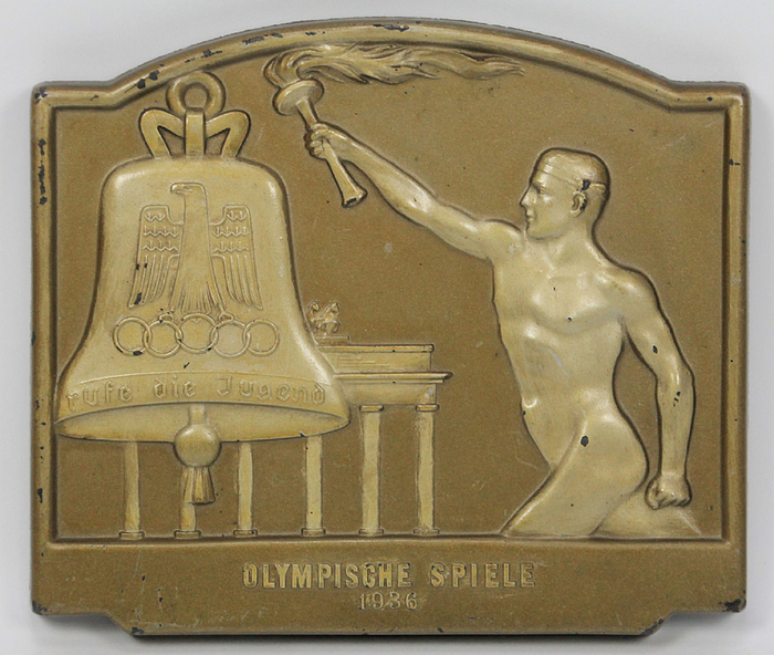  - Large torch relay plaque "Olympic Games 1936". Featuring torchbearer, Brandenburg Gate and the Olympic Peace Bell. Fired plaster, brown lacquered. 19.5 x 17 cm. --Very nice wall plaque. With small chips. Condition: B