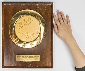  - Official UEFA plaque of honor for the DFB on the occasion of the 1980 European Champions Cup final in Madrid. Large, gold-plated UEFA logo plaque (20 cm) mounted on a wooden plate. With attached engraved brass plaque with the inscription "25th final of the European Champion Clubs' Cup Hamburger SV - Nottingham Forest. Madrid, May 28, 1980" (0:1 goal). Manufacturer: Huegenin, Susse. 35x28cm. Museum piece! --Back with wall hanging. Three plaques were made! On the occasion of the UEFA Cup finals, UEFA awarded these plaques to the national football associations from which the final participants came and to the national association of the final venue in which the final was played. The engraved plaques with the pairings were made in the corresponding national language (this plaque in German, English or Spanish). From around 2000 the appearance of these plaques changed; the UEFA plaque is made of ceramic and was mounted on a light metal plate. Plaque comes from the collection of a former high DFB official.  --Signs of use. The step plaque had come loose and was reinstalled. Condition: B - Bild 2