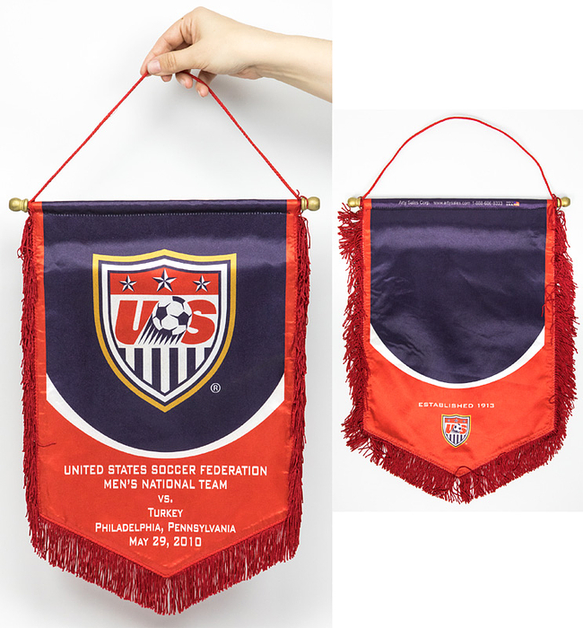  - Original match pennant of the US Men's National Soccer Team. Silk-printed pennant with the inscription "United States Soccer Federation. Men's National Team vs. Turkey. Philadelphia, Pennsylvania. May 29, 2010" (1-2). Gold-plated wooden balls with a wooden pole. Red silk fringes. 43 x 29 cm. --This pennant was awarded to Türkiye and the referees. The pennant came from one of the referees of this match. Condition: A