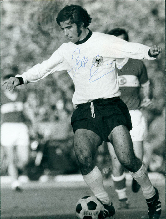 Müller, Gerd  | (1945-2021) s/w-Pressefoto (Horst Müller) mit Originalsignatur von Gerd Müller im Trikot der deutschen Nationalmannschaft bei der Fußball - eltmeisterschaft 1974. Deutscher Fußball-Weltmeister 1974 und WM-Teilnehmer 1970, Bayern München. 20.5x15 cm.