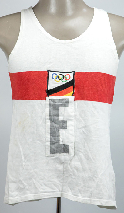 1Fütterer, Heinz - Trikot OSS1956  | Original Olympiatrikot des deutschen Sprinters Heinz Fütterer (1931-2019) der bei den Olympischen Spielen Melbourne 1956 in diesem Trikot die Bronzemedaille in der 4x100 m Staffel gewann. Baumolle, Größe 5, mit aufgenähtem beticktem Stoffabzeichen der gesamtdeutschen Mannschaft für Olympia 1956 und einem aufgenähten mit einem "E" bedrucktem Leinenetikett für Staffelläufer. Marke: Leuzela. Auf der Rückseite ebenfalls ein Leinenetikett mit "E". Tragespuren. Fotomatched (https://www.faz.net/aktuell/sport/mehr-sport/der-weisse-blitz-heinz-fuetterer-ist-tot-16034195.html). Status:AAB --Museumstück!!!.
