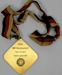  - Two winner's medals from the 1979 and 1980 East German Boxing Championships: 1) Gold medal inscribed "1979 East German Championship Senior Featherweight" with silk ribbon. 2) Bronze medal "1980 East German Championship Senior Light Middleweight" with silk ribbon. Each 8x8 cm in original box. Also included: an honorary plaque of the German Boxing Association (DBV) - East Germany with the inscription "Honorary Plaque Gerd Lang" on the reverse. Gilt bronze with an applied, enameled state coat of arms, 8.5x8.5 cm. --signs of usage Condition: B - Bild 3