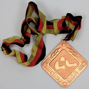  - Two winner's medals from the 1979 and 1980 East German Boxing Championships: 1) Gold medal inscribed "1979 East German Championship Senior Featherweight" with silk ribbon. 2) Bronze medal "1980 East German Championship Senior Light Middleweight" with silk ribbon. Each 8x8 cm in original box. Also included: an honorary plaque of the German Boxing Association (DBV) - East Germany with the inscription "Honorary Plaque Gerd Lang" on the reverse. Gilt bronze with an applied, enameled state coat of arms, 8.5x8.5 cm. --signs of usage Condition: B - Bild 4