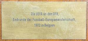  - Large official participant plaque for the German Football Association (DFB) commemorating their participation in the final tournament of UEFA EURO 1972 in Belgium. Each participating national association received one of these plaques. The plaque is made of oak with a large UEFA logo screwed onto it. It features a gilded brass plaque, manufactured by "Huguenin" (21 cm), and a mounted engraved brass plaque (8 x 3.5 cm) inscribed "UEFA to the DFB Final Tournament of the 1972 European Football Championship in Belgium". The overall dimensions are 35 x 28.5 cm. A unique piece. A museum piece! --Germany won the 1972 European Football Championship. A total of four of these commemorative plaques were issued to the participating associations. These solid plaques are designed for wall mounting. Never before offered for sale.  ----The plaque comes directly from the holdings of a private football museum and has already been exhibited in various public exhibitions. Condition: A- - Bild 4