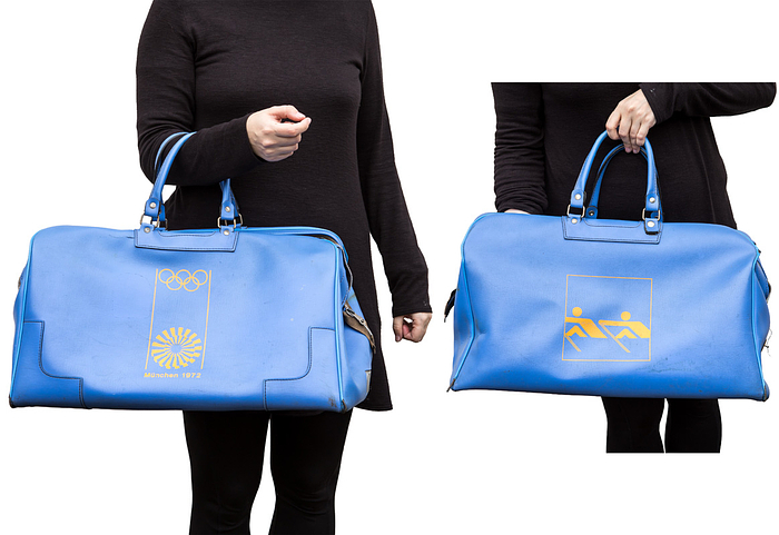  - Large faux leather sports bag with the printed logo of the 1972 Munich Olympic Games and the Otl Aichner logo for "rowing". 50x30x28 cm --According to the consignor, this bag belonged to a member of the West German rowing team at the 1972 Olympics. The bag shows signs of wear; one handle has been professionally repaired; the zipper lock is missing. Zipper is functional. Condition: B