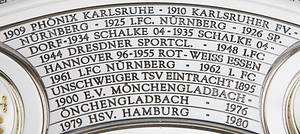 DFB-Meisterschale 2024 Bayer Leverkusen  | Offizielles Replikat der DFB-Meisterschale für die Saison 2023/24 für den deutschen Meister 2024 Bayer Leverkusen. Der jeweilige deutsche Meister hat das Recht Replikas in dieser Größe offiziell anfertigen zulassen.  Letzte Inschrift auf der Schale "Bayer Leverkusen 2024". Versilbert, Messing, ziervergoldet, Gravuren. Hersteller: Koch & Bergfeld, Bremen. Gewicht: 6,6 kg, Durchmesser 52 cm. Mit original Koffer, innen mit geprägtem DFB-Logo. 59x59x18cm. Mit original Signaturen von Xabi Alonso, Florian Wirtz, Jonathan Tah und Robert Andrich. Weil die Spieler von Bayer Leverkusen von ihrem Trainer Xabvi Alsonso anläßlich der Deutschen Fußballmeisterschaft eine kleine Meisterschale (ca. 18 cm) aus Silber bekamen, machte keiner der Spieler von seinem Recht  gebrauch sich von der Firma Koch & Bergfeld eine fast 1:1 Kopie der orignal Meisterschale anfertigen zu lassen. Es wurden laut Aussagen des Einlieferes lediglich zwei Exemplare produziert. Ein Exemplar befindet sich im Museum / Klubräumen von Bayer Leverkusen in der BayArena. Das andere Exemplar wird in dieser Auktion angeboten. Mit original Plexiglasständer für diese Meisterschale. EIN HIGHLIGHT FÜR JEDE SAMMLUNG!. - Bild 8