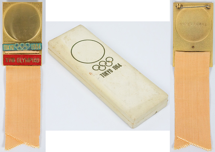 Teilnehmerabzeichen 1964  | Offizielles Teilnehmerabzeichen Tokyo 1964 „XVIII Olympiad“. Für Sonderdelegierte. Bronze, vergoldet. Schriftleiste rot emailliert. Seidenband in sandfarben. 14x3,8cm. In original Box.