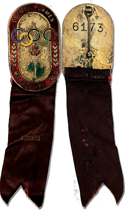 1)Teilnehmerabzeichen 1956  | Teilnehmerabzeichen „Olympic Games Melbourne 1956“. Nummeriertes Abzeichen „6173“. Bronze, mehrfarbig emailliert. Mit violetten Seidenband und Aufdruck „Football“. 12,5x3,1 cm.