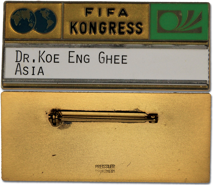 Teilnehmerabzeichen 1974  | Teilnehmerabzeichen „FIFA Kongress 1974“ in München. Mit Namensschildchen aus Karton "Dr. Koe Eng Ghee Asia". Bronze, vergoldet, mehrfarbig emailliert, 7x3,2 cm.