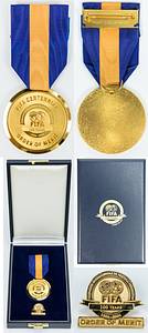 FIFA Order of Merit Gold 2004 World Cup - FIFA medal “FIFA Centennial ORDER OF MERIT” 2004 in gold. In original cassette with associated medal pin. Size of the cassette 16.5x11xx3.5 cm; “Order of Merit” gold-plated, 4.5 cm with original silk ribbon; Pin, gold-plated, 2.5x2.2 cm. --The FIFA Order of Merit is the highest honor awarded by FIFA. It is awarded in gold and silver. The Golden Order is only issued very rarely. This medal was awarded for the first time in 1984. These awards only go to personalities “who have had a significant impact on football events in the past”. The first recipients of this Medal of Honor were Sir Stanley Rous, Bobby Charlton, Helmut Schön, Franz Beckenbauer and Michele Platini. This special "Order of Merrit" was created for FIFA's 100th anniversary. John Warren was the only person to receive this award this year. But previous recipients of the order were honored again by this special "Order of Merrit" on the occasion of the FIFA gala in Paris in 2004, e.g. Pele (whose medal was sold in Los Angeles in the "Pele auction" in 2016), Beckenbauer, Platini ect.. Very nice piece in original leather case. Uncirculated. (EF). Condition: A - Bild 7