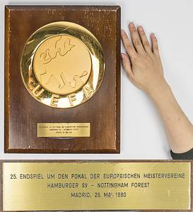 HSV - UEFA-Plakette Cup-Final 1980  | Offizielle Ehrenplakette der UEFA für den DFB anlässlich des Europapokalendspieles der Meister 1980 in Madrid. Große, vergoldete UEFA Logoplakette (20 cm) aufmontiert auf Holzplatte. Mit aufgesetzter gravierter Messingplakette mit der Inschrift "25. Endspiel um den Pokal der Europäischen Meisterveriene Hamburger SV - Nottingham Forest. Madrid, 28.Mai 1980" (0:1 Goal). Hersteller: Huegenin, Susse. 35x28 cm. Museumstück!. - Bild 4