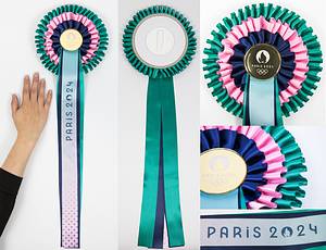 Siegermedaille 2024  | Original Siegerrosette für den 1.Platz bei den Olympischen Spielen Paris 2024 in den Reiterbewerben für die Pferde. Dreifarbige Seidenrosette im Zentrum eine goldfarbene Kunststoffplakette mit den Olympischen Ringen und der Aufschrift "Paris 2024", Durchmesser der Rosette 20 cm. Mit fünf langen Seidenbänder, ein Band mit der Aufschrift "Paris 2024", Länge: 51 cm. Rückseite mit Kunststoffhalterung zur Anbringung bei der Siegerehrung am Pferdehalfter. - Bild 7