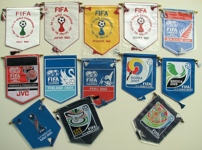 FIFA pennants " U-17 World Championship" 1991 -15 - 13 FIFA pennants "U-17 World Championship" from the years 1991 to 2015. Silk pennant, multi-colored embroidered, one printed, silk border, with crom or brass rod and corresponding balls, silk tassels. Approx. 24.5x22 cm. Were handed over only to team members, referees and officials !! Condition: A-