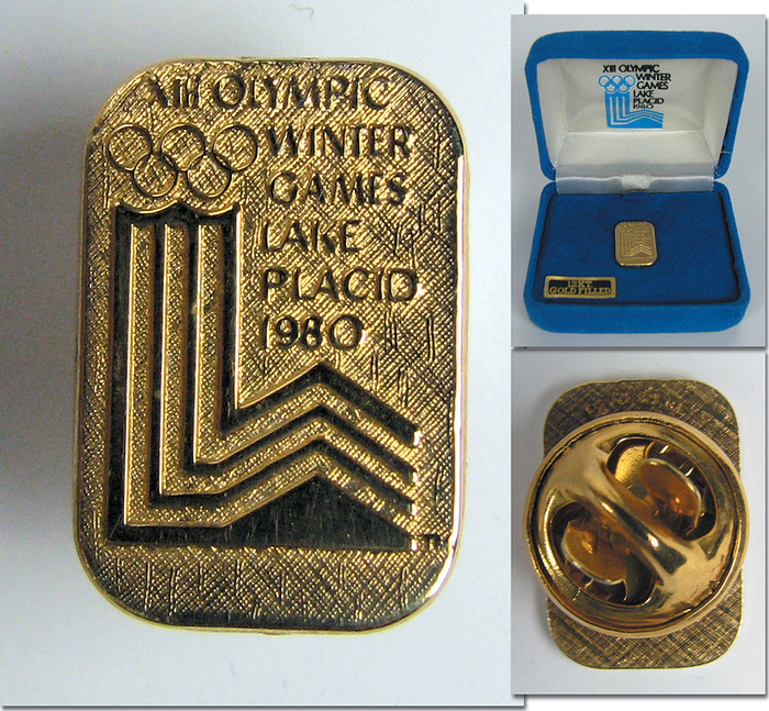 Olympische Spiele 1980  | Offizieller goldener Besucherpin für die Olympischen Winterspiele 1980 in Lake Placid. 12 Karat Gold Filled Gold, 1,2x1 cm. In original samtbezogener Box mit eingedrucktem Logo der Olymischen Winterspiele.