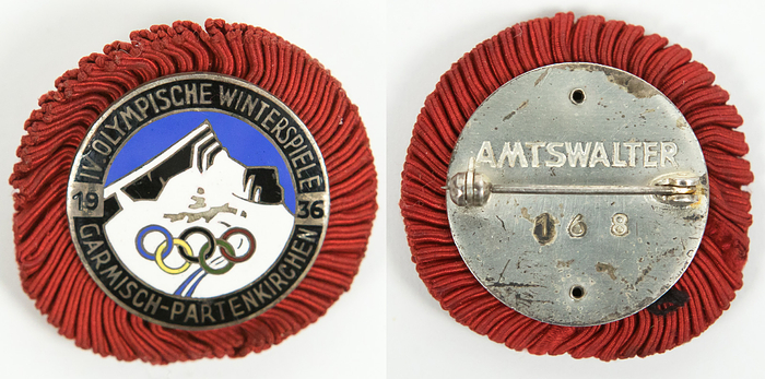 Teilnehmerabzeichen 1936  | Olympischen Winterspiele Garmisch-Partenkirchen 1936. Teilnehmerabzeichen für Offizieller des Organisationskomittees. Bronze, versilbert. Mehrfarbig emailliert, Rückseite mit Gravur „Amtsalter 168“. Mit rote Stoffrosette, 4x3,5 cm.