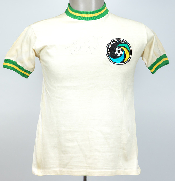  - New York Cosmos fan jersey, hand-signed by football legend Pelé with the inscription "Edson Pelé." The autograph was obtained in Paris in the late 1970s. Cotton; features a sewn-on, embroidered New York Cosmos club crest. Size: approx. S. --Signature slightly faded! Condition: A-