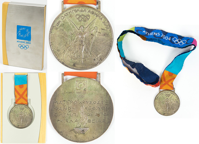 Siegermedaille 2004  | Silbermedaille für den 2.Platz im Judo bei den Olympischen Spielen Athen 2004. Mit Gravur Frauen Judo +78 kg (in griechisch). Silber (ca. 140 Gramm), 6 cm mit original Seidenband. Original Box für die Siegermedaille der Olympischen Spiele Athen 2004. Holzkiste mit Kunstsoffeinlage für Medaille mit einem verchromten Metallschuber. Diese mit aufdedruckten Loge der Olympiade 2004, 18x11,5x2. In original Karton.