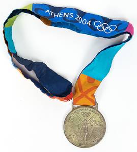  - Olympic Games 2004: Silver medal for 2nd place in Judo at the 2004 Athens Olympic Games. Engraved: Women's Judo +78 kg (in Greek). Silver (approx. 140 grams), 6 cm in diameter, with original silk ribbon. Original presentation case for the winner's medal from the 2004 Athens Olympics. Wooden box featuring a synthetic insert for the medal and a chrome-plated metal sleeve. The sleeve bears the printed logo of the 2004 Olympiad; dimensions: 18 x 11.5 x 2 cm. Housed in its original cardboard outer box.  Medal tarnished. Minor signs of wear. The buyer will be informed of the athlete's name. Condition: A- - Bild 5