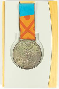  - Olympic Games 2004: Silver medal for 2nd place in Judo at the 2004 Athens Olympic Games. Engraved: Women's Judo +78 kg (in Greek). Silver (approx. 140 grams), 6 cm in diameter, with original silk ribbon. Original presentation case for the winner's medal from the 2004 Athens Olympics. Wooden box featuring a synthetic insert for the medal and a chrome-plated metal sleeve. The sleeve bears the printed logo of the 2004 Olympiad; dimensions: 18 x 11.5 x 2 cm. Housed in its original cardboard outer box.  Medal tarnished. Minor signs of wear. The buyer will be informed of the athlete's name. Condition: A- - Bild 6