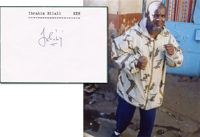 Bilali, Ibrahim  | Blancobeleg (10,5x7,5 cm) mit original Signatur von Ibrahim Bilali (KEN). Bronzemedaille im Boxen bis 48 kg bei den Olympischen Spielen 1984. Mit Farbfoto montiert mit Fotoecken auf DIN A4 Blatt.