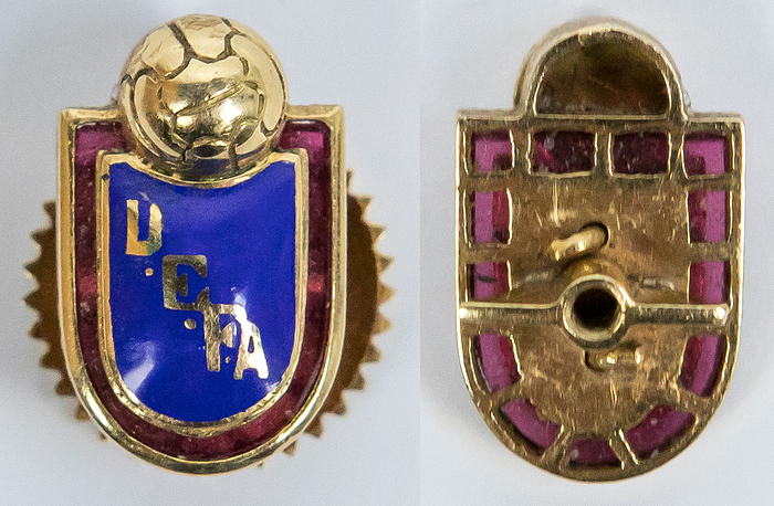  - Golden UEFA Pin for Vicepresident app.2006: UEFA badge for the vice president circa 2006. Gold (750) with transparent violet backing. Applied blue enamel coat of arms with hand-painted lettering “UEFA”. Back with gold screw engraved with the Vice President's initials. Jewelery production. 2x1.2cm --Probably unique! Comes directly from the collection of the former UEFA Vice President. Condition: A