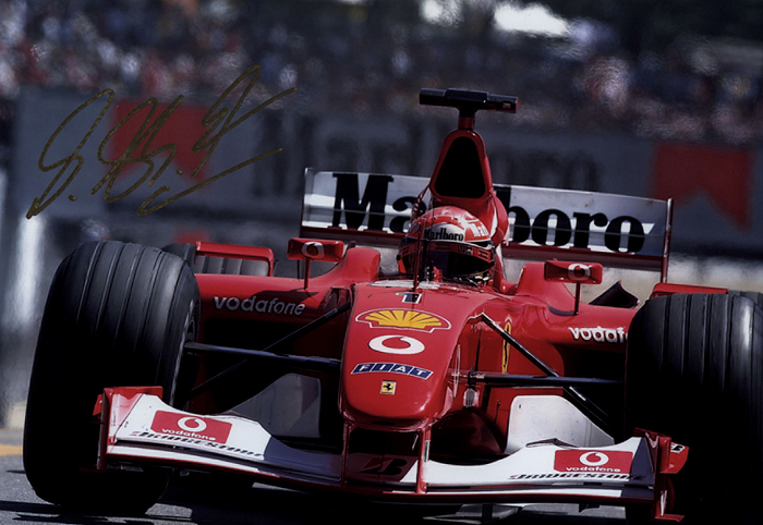 Schumacher, Michael  | Großer Farbdruck Michael Schumacher im Ferrari mit Originalsignatur mit Goldstift vom 7-fachen Formel 1-Weltmeisters Michael Schumacher. 30x20cm. Mit Echtheitszertifikat von "Tamper Seal".