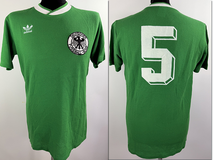  - Original match-issued DFB player shirt Number 5belonging to Matthias Herget. Prepared for the 1986 FIFA World Cup Final between Germany and Argentina, held on June 29, 1986, at the Estadio Azteca (Mexico City). The shirt comes from the collection of German international Matthias Herget, who sat on the substitutes' bench during the final. Status: AAA. Short-sleeve jersey; Size 7/8 (Large); Sewn-on DFB eagle crest; Rubberized manufacturer logo; Back number applied via wet-flock transfer; 56% Cotton, 44% Polypropylene; Climalite 2000; Made in West Germany. Condition: A