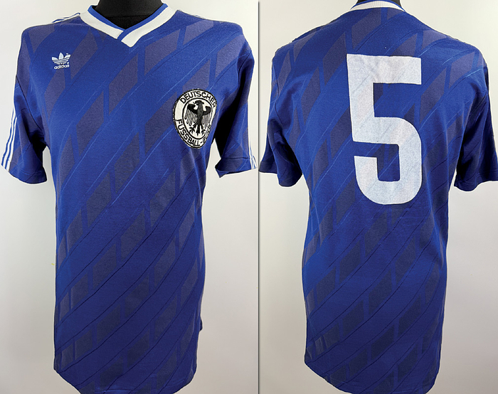DFB - Trikot 1986  | Original match worn DFB Spielertrikot der mit der Nummer 5 von Matthias Herget.Getragen am 24.05.1986 im Freundschaftsspiel gegenden maexikanischen Erstligisten Atletico Morelia. In diesem Spiel lief die deutsche Nationalmannschaft in ungewohnten blauen Trikots auf, bis heute ein einmaliger Anblick in der DFB Geschichte. Hintergrund war eine damalige FIFA-Vorgabe: Bei inoffiziellen Testspielen durfte keine offiziellemn Matchtrikots verwendet werden. Trikot stammt aus der Sammlung von deutschen Nationalspieler Matthias Herget. Status AAA